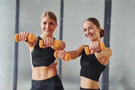 Uses Dumbbells Two Women In Sportive Wear And With Slim Bodies Have Fitness Yoga Day Indoors