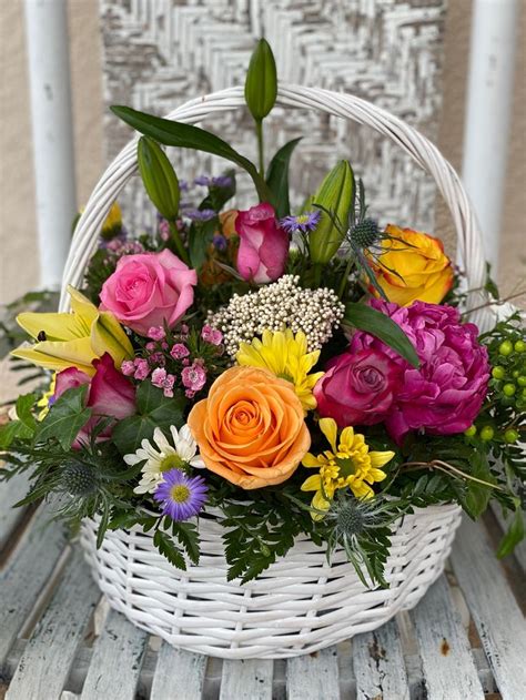 A Basket Filled With Flowers Sitting On Top Of A Wooden Table Next To A