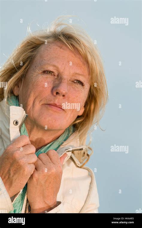 Upper Body Portrait Of A Blond Mature Woman In Bright Jacket Covered Sky Dreamy To The Side