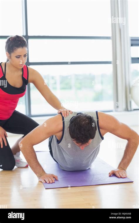 Female Trainer Assisting Man With Push Ups In Gym Stock Photo Alamy