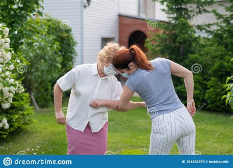 Two Masked Women Greet Their Elbows In The Park An Elderly Woman And