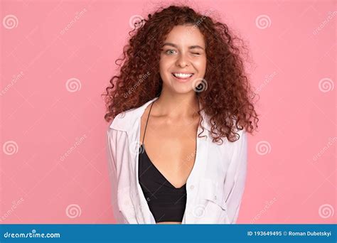 Pretty Cheerful Redhead Girl With Curly Hair Smiling Looking At Camera Over Pink Background