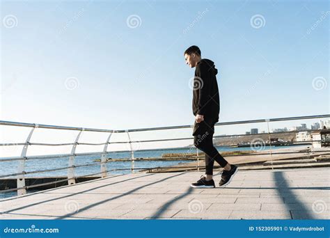 Photo Of Joyful Guy 20s Walking Along Wooden Boardwalk By Seaside After