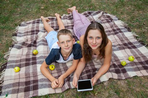 Young Sister And Brother Lying Down And Work With Tablet Stock Photo