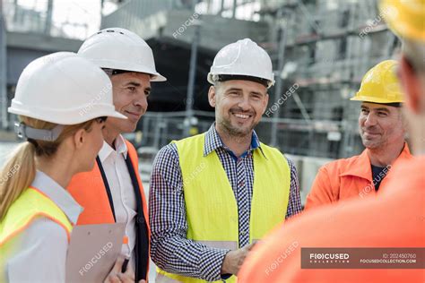 Smiling Engineers And Construction Workers Meeting At Construction Site