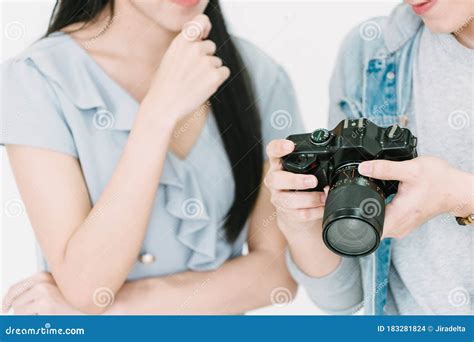 asian photographer and asian female model looking pictures from back screen of dslr camera with