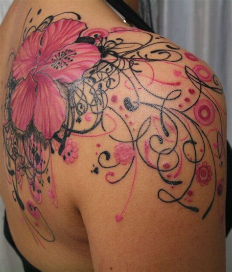 The Back Of A Womans Shoulder With Tattoos On It And Flowers In The Middle