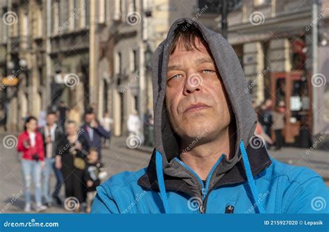 street portrait of a 45 50 year old man with a serious expression in a gray hoodie on his head