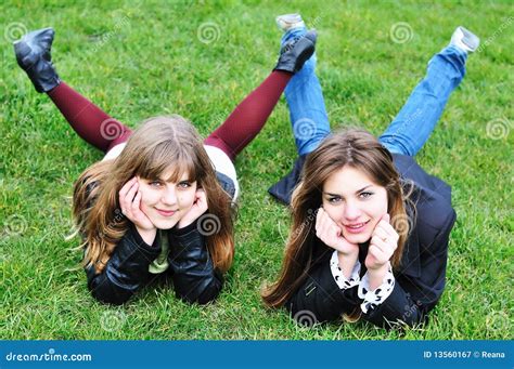 Two Girls Laying Upside Down On A Grey Sofa With Legs Up Stock Image