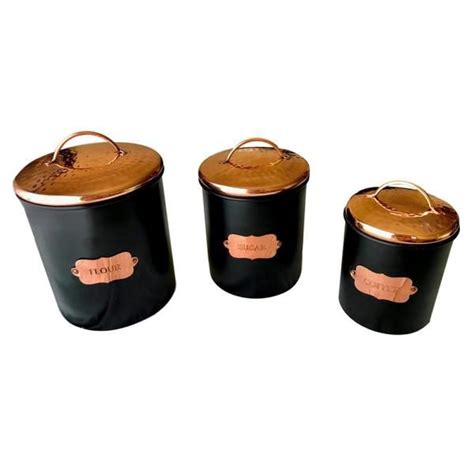 Three Black And Copper Canisters With Labels On Them
