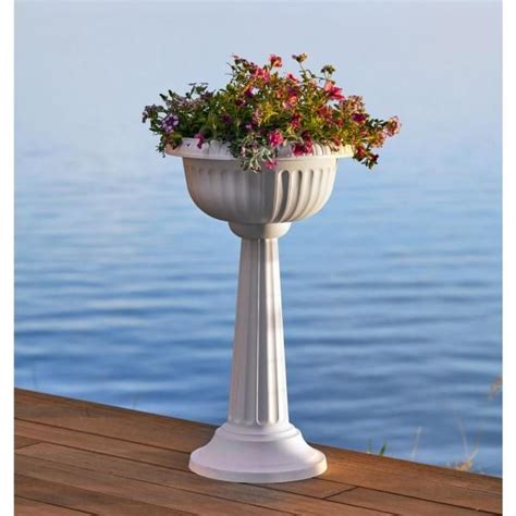 There Is A White Vase With Flowers In It On The Deck By The Waters Edge
