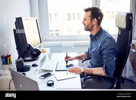 Smiling Graphic Designer Working On Computer At Desk In Office Stock