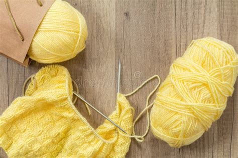 Light Yellow Knitting Wool And Knitting Needles On Wooden Background