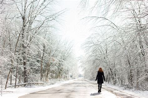 redhead woman walking on icy road in winter with snow by stocksy contributor jp danko stocksy