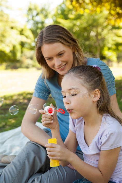 Mother With Her Daughter Blowing Soap Bubbles At Park Stock Image