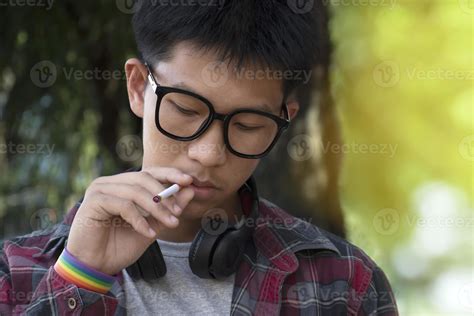 Young Asian Teen Boy In Plaid Shirt Wears Rainbow Wristband And Holds