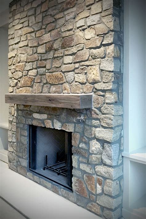 White country squire stone veneer is the featured wall stone in a mortared stone veneer masonry application for the fireplace stone, with a cozy seating area and floating wood shelves for the perfect home decor. Pin on FIELDLEDGE Full & Thin Stone Veneer Masonry - Fieldstone & Ledgestone Veneer