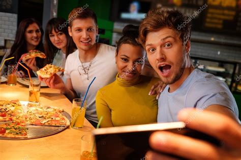 Multiracial Friends Having Fun Eating Pizza In Pizzeria Stock Photo By