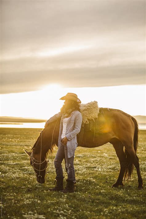 Cowgirl Standing Beside A Horse At Sunset By Stocksy Contributor