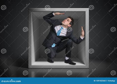 Young Businessman Trapped Inside Uncomfortable Small Box Stock Photo