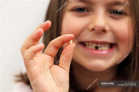 Portrait Of A Gap Toothed Girl Holding Her First Milk Tooth Thats