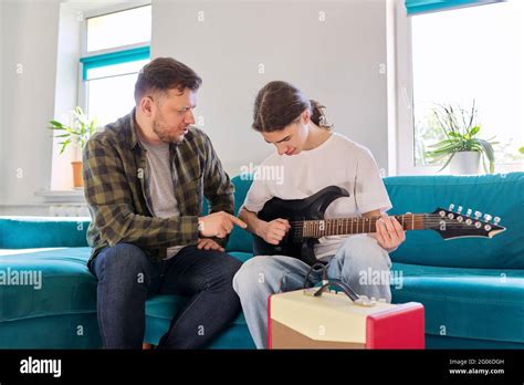 Father Teaches His Teenage Son To Play The Electric Guitar Stock Photo