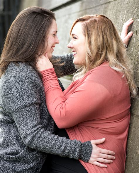 Two Women Hugging Each Other While Leaning Against A Wall
