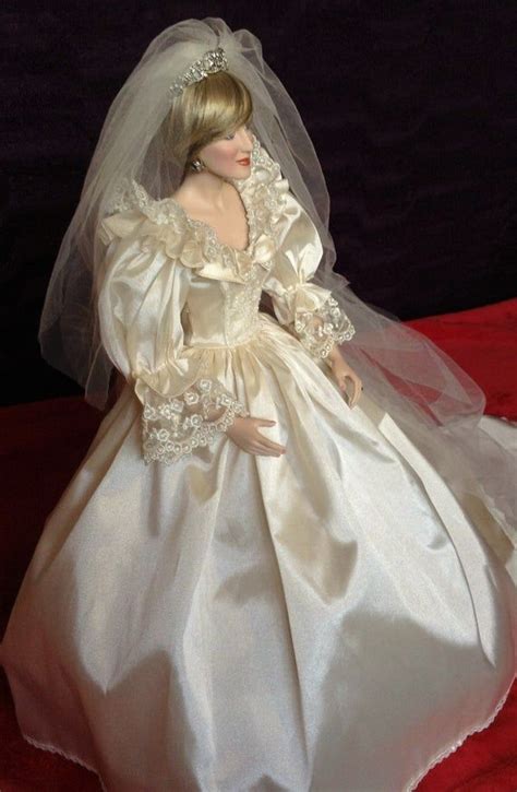 A Doll Dressed In A Wedding Dress And Veil On A Red Cloth Covered