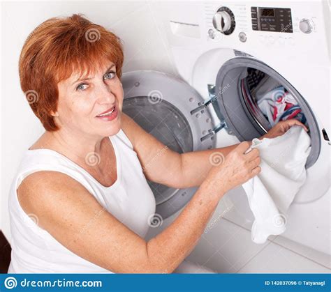 Woman Puts Clothes In The Washing Machine Stock Photo