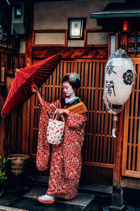 A Geisha Woman Holding An Umbrella In Her Hand
