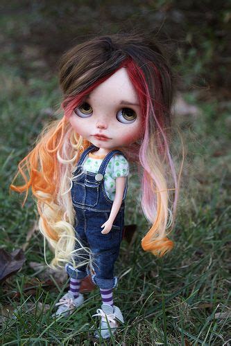 A Doll With Blonde Hair And Blue Overalls Standing In The Grass Next To