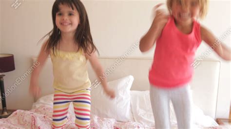 Two Young Girls Bouncing Excitedly On Bed Looking Stock Video Footage