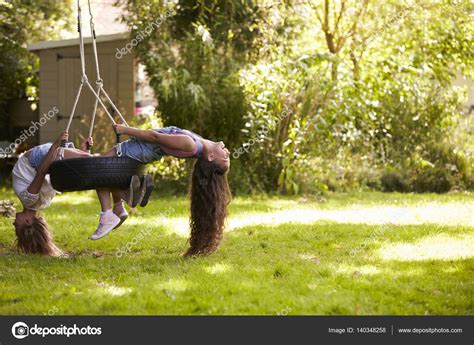 Two Girls Playing On Tire Swing Stock Photo Monkeybusiness