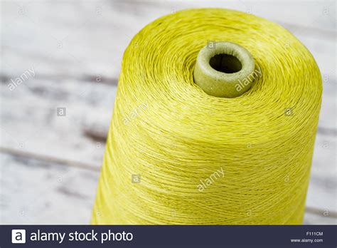 Spool Of Synthetic Green Thread On White Wooden Background Stock Photo
