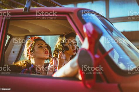 Happy Pinup Girls Driving Vintage Car And Applying Makeup Stock Photo