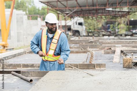 Construction Worker Uses Long Steel Trowel Spreading Wet Concrete