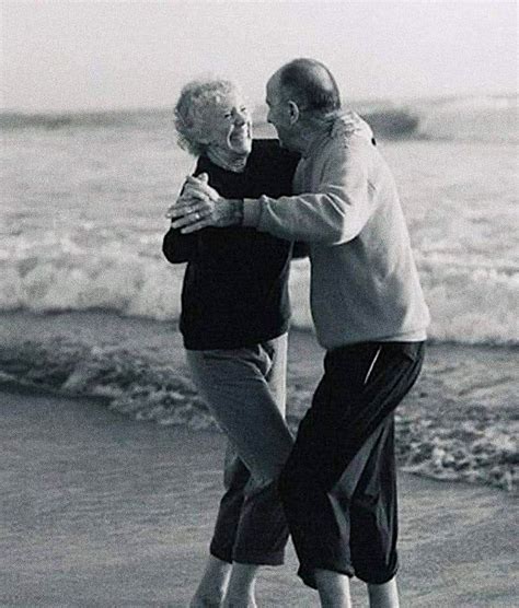 An Older Man And Woman Hugging On The Beach