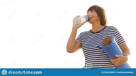 Mature Woman Drinking Water From Bottle After Fitness Exercises Or Yoga