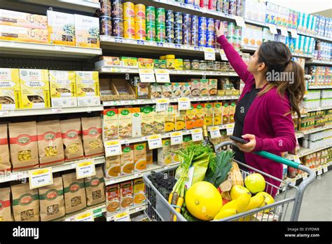 Woman Reaching For Canned Food From Supermarket Shelf Stock Photo Alamy