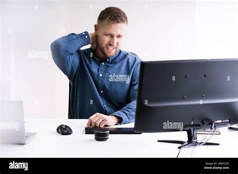Young Businessman In Office At Desk Suffering From Neck Pain Stock