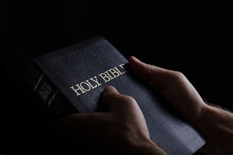 Man Holding The Holy Bible In A Dark Setting Stock Photo Download