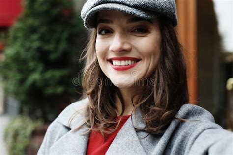 Stylish Pretty Woman Wearing Red Dress Grey Coat And Hat Posing In The