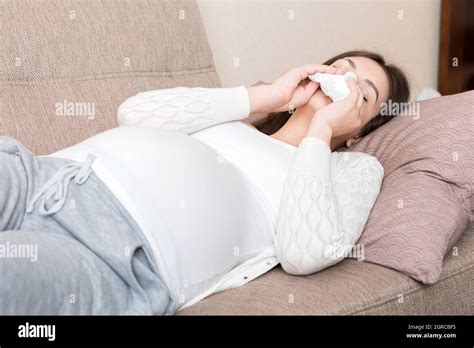 Sick Pregnant Woman Blowing Nose Into Tissue At Home Healthy Millennial Healthcare Concept Stock