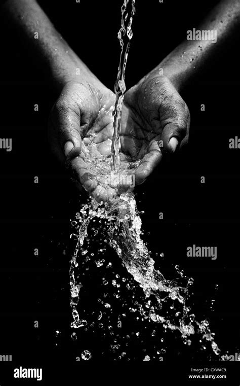 Indian Mans Cupped Hands Catching Poured Water Against Black Background