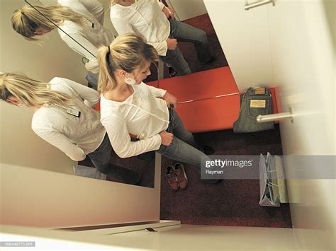 Young Woman Trying Clothes In Dressing Room Cubicle Overhead View Photo