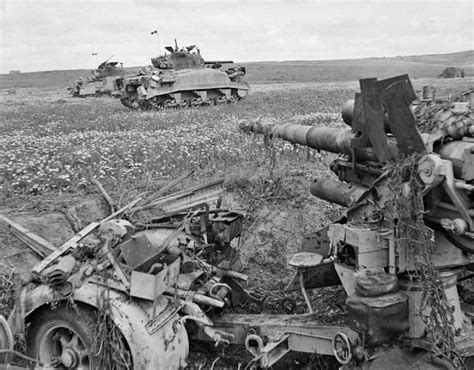 Two Tanks Are In The Middle Of A Field With Other Vehicles Behind Them