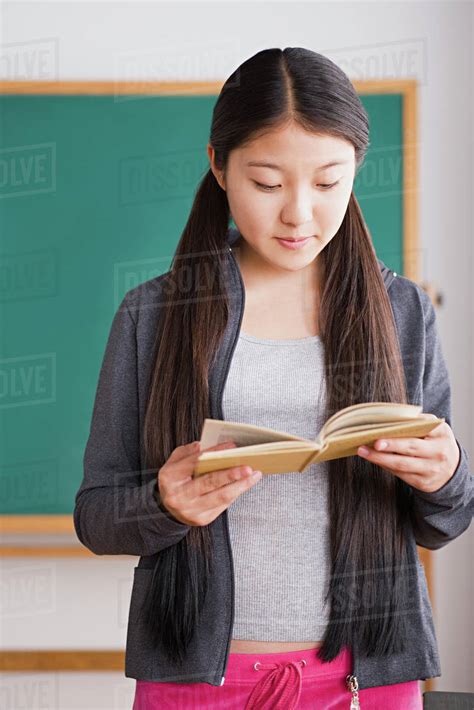 Schoolgirl Reading Book In Front Of Blackboard Stock Photo Dissolve