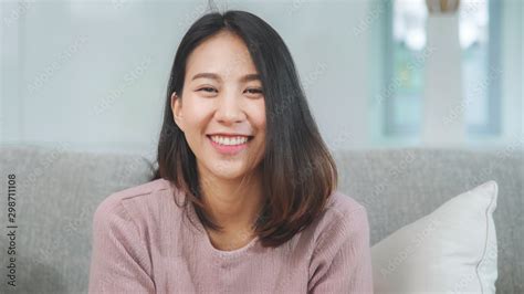 teenager asian woman feeling happy smiling and looking to camera while relax in living room at