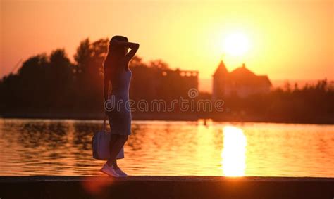 Back View Of Lonely Woman Standing On Lake Side On Warm Evening