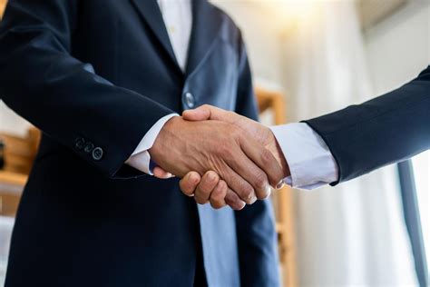 Two Businessmen Shake Hands To Seal A Negotiation Deal At Work 1103229